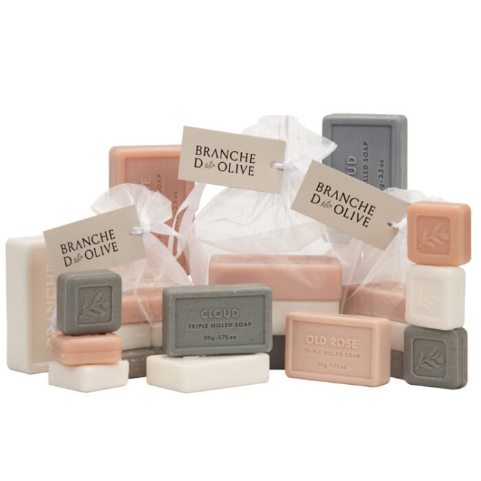 Group shot of Branche d'Olive bagged and tagged soaps in various sizes, 100g, 50g & 25g with unbagged samples also shown all in the three fragrances of Cloud, Lily/Valley & Rose