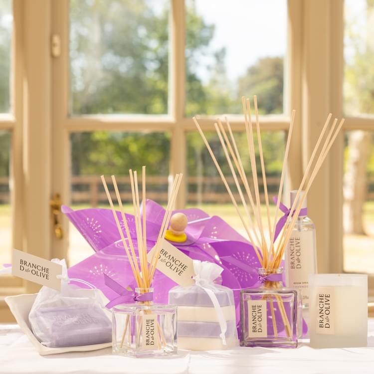 A selection of Branche d'Olive's Lavender fragrance range including diffuser, candle, bagged soap and soap in draining soap dish.