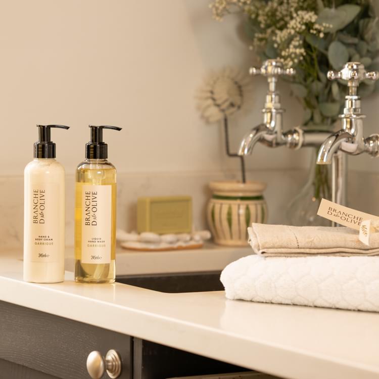 Branche d'Olive Garrigue hand wash and Garrigue hand cream set in laundry setting with taps and towels, soap and brushes