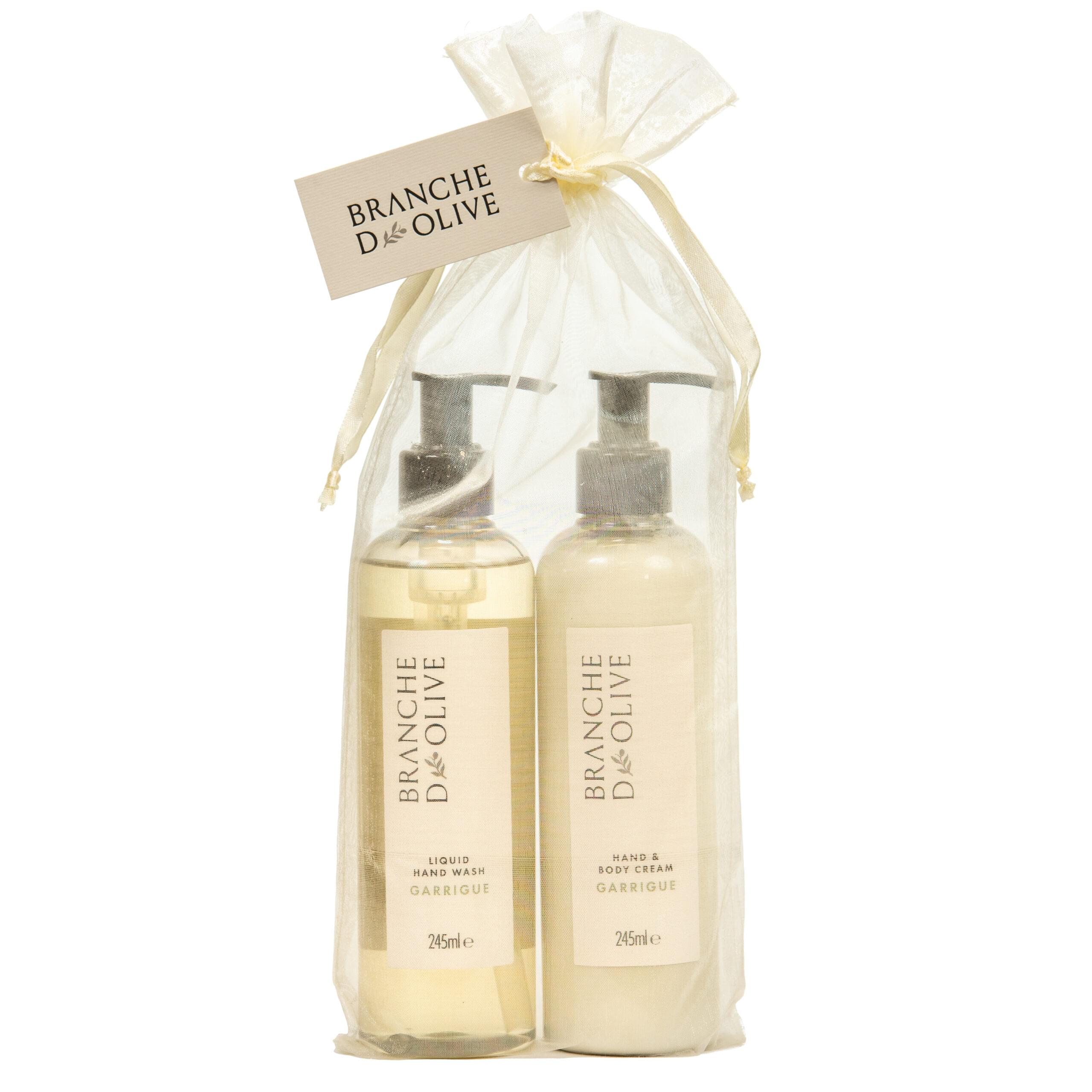 Two pumped bottles, bagged and tagged with Branche d'Olive's Garrigue luxury hand wash and hand/body lotion set against a white backdrop