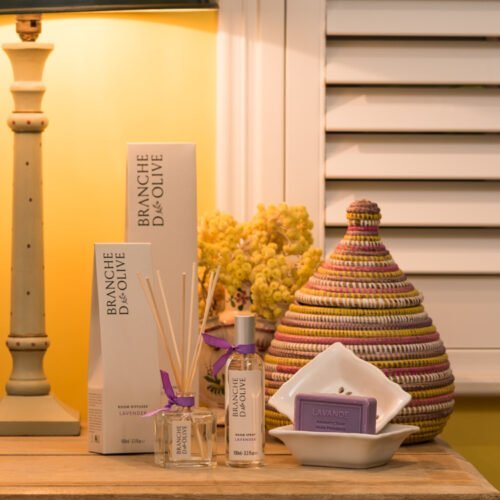 Branche d'Olive Lavender Room Diffuser, Room Spray, Soap and Soap Dish on a wooden table in front of some yellow flowers