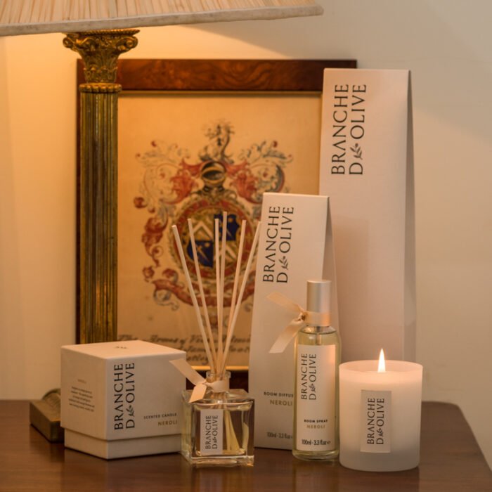Branche d'Olive Neroli scented Room Diffuser, Room Spray and Candle on a wooden table in front of a classic picture