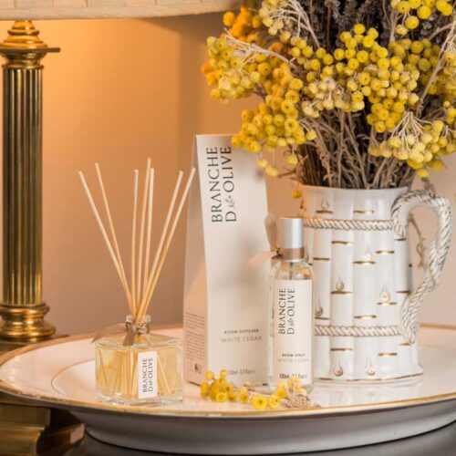 Branche d'Olive White Cedar scented Room Diffuser and Room Spray next to a jug of yellow flowers